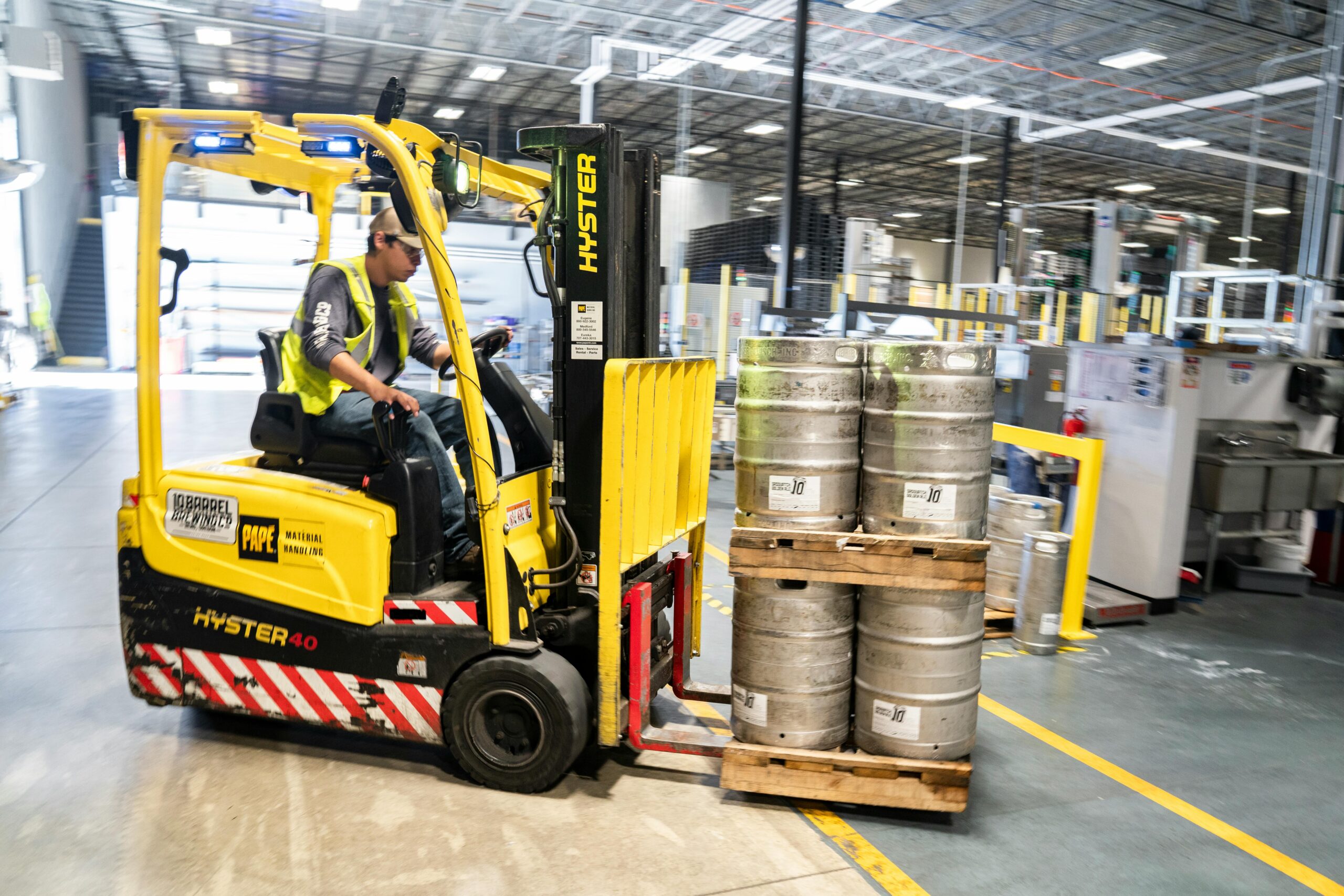 Man driving forklift with propane tanks on a pallet.